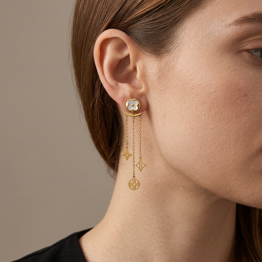 Model wearing gold mother-of-pearl clover ear-jacket earrings with three dangling chains.