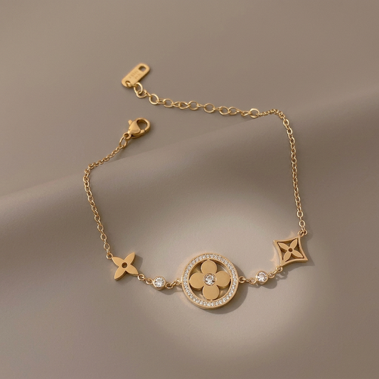 Gold CZ clover bracelet with flower charms on a warm-gray background matching the necklace photo.