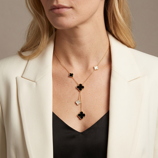 Model in an ivory blazer wearing a gold five-clover lariat necklace with black and white charms.