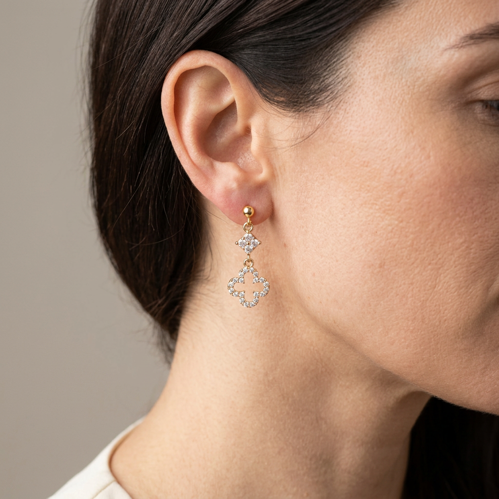 Model wearing crystal open clover dangle earrings with gold ball studs
