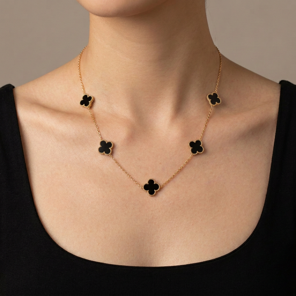 Model wearing a gold necklace with five black clover motifs.