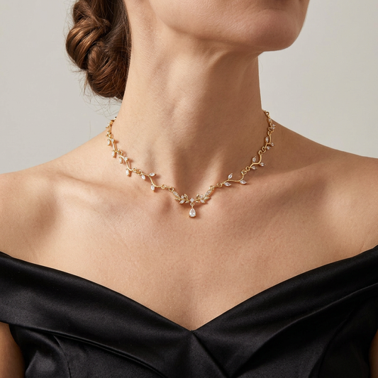 Gold leaf vine necklace with clear crystals and a small central teardrop worn with a black satin gown