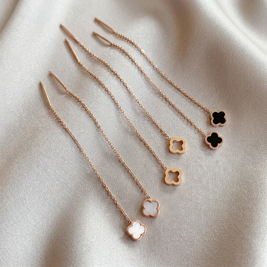 Six rose gold threader clover earrings on warm gray silk