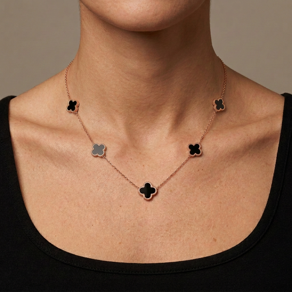 Model wearing a rose-gold necklace with five small black clover charms.
