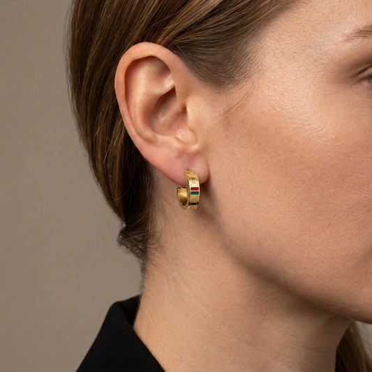 Close-up of a model wearing a small gold GG huggie hoop with red and green enamel panels.