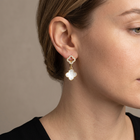 Model wearing gold double-clover earrings with a crystal openwork clover and mother-of-pearl drop.
