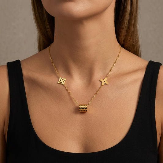 Model wearing a delicate gold necklace with two side motifs and a patterned barrel pendant.