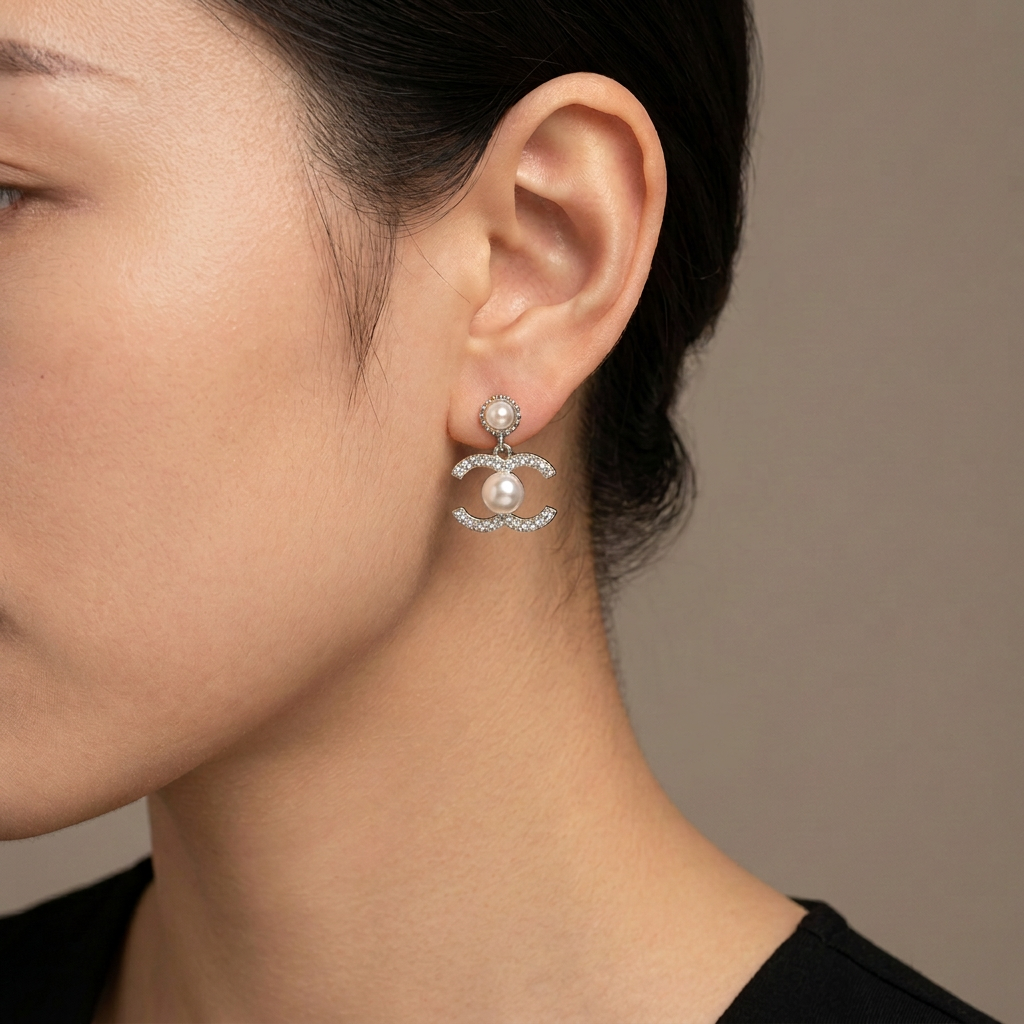 Model wearing silver double-C crystal and pearl drop earrings.