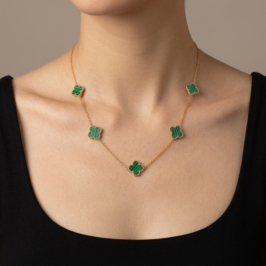 Model wearing a gold necklace with five striped green clover motifs.